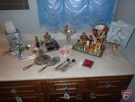 Perfumes, dresser set, makeup brushes, trinket brushes, trays. All items on counter