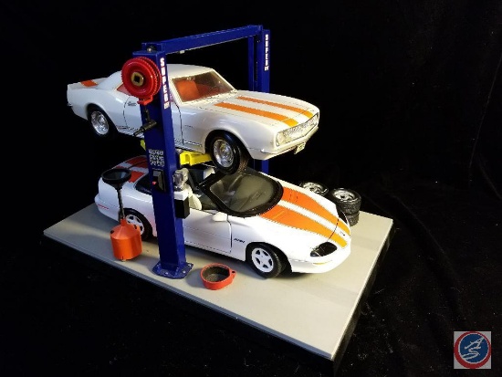 (2) die cast Camaros in car shop display, with bend pack super lift and spare tires