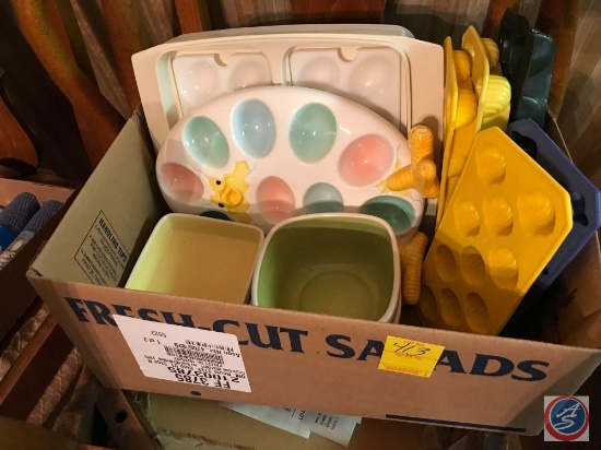 Box containing Easter themed dish ware including ice cube trays, deviled egg serving dish, bowls,