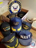 Box containing Navy metal wall hanging, navy hats and patches
