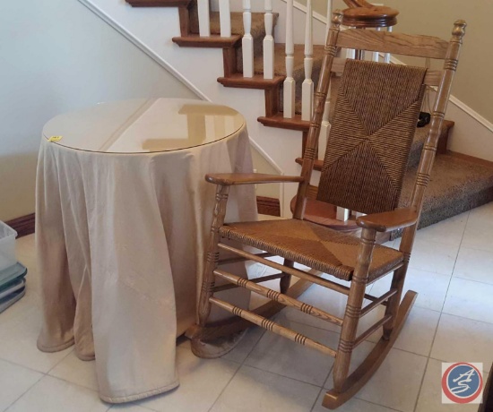 Small round wood table with glass top and gold colored decorative cloth, wood with woven seat and