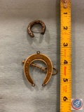 Two horseshoes one is standard silver and it?s a pen the other one is a necklace or a charm mother