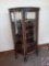 Antique Curved glass china cabinet w/ mirrored top shelf. Rounded brass pull w/ key in lock & claw