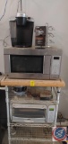 Oster toaster oven, Keurig coffee maker, GE microwave, on a metal shelf with butcher block top