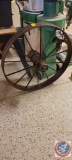 Large metal wheel. There is some rusting and moss on the wheel.