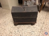 A vintage toolbox on wheels filled with miscellaneous items.