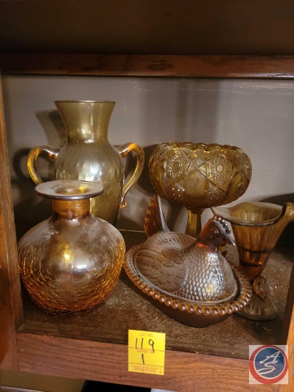 Assorted amber colored glass items. Items include Chicken covered basket, and vases. There are