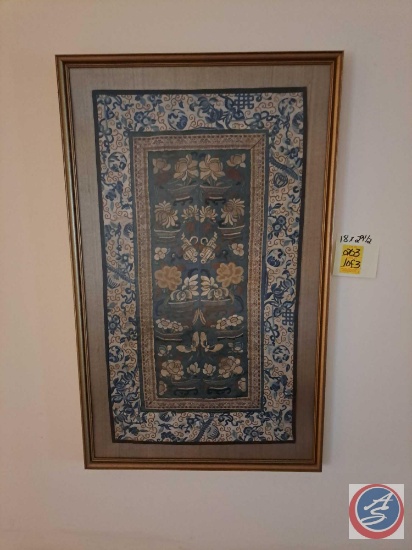 Two framed Asian inspired tapestries and a decorated fan. The first tapestry measures at 18 inches