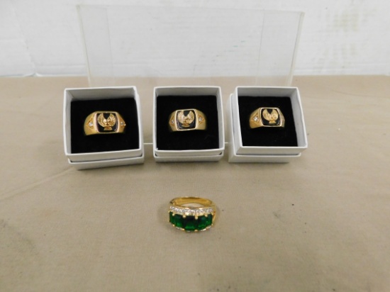 (3) MENS GOLD TONE EAGLE RINGS & (1) WOMANS GOLD TONE W/ GREEN STONES RING