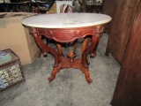 VICTORIAN OVAL MARBLE TOP TABLE WITH CARVED LEGS AND WOODEN WHEELS