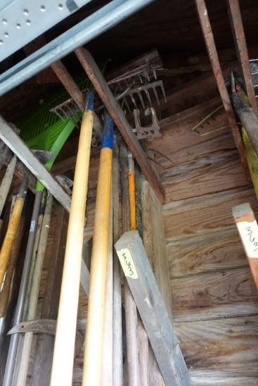 CORNER LOT IN GARAGE INCLUDING RAKES HOES NETS PICK AXES AND MORE