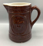 Brown Pottery Pitcher With Embossed Cows, 8