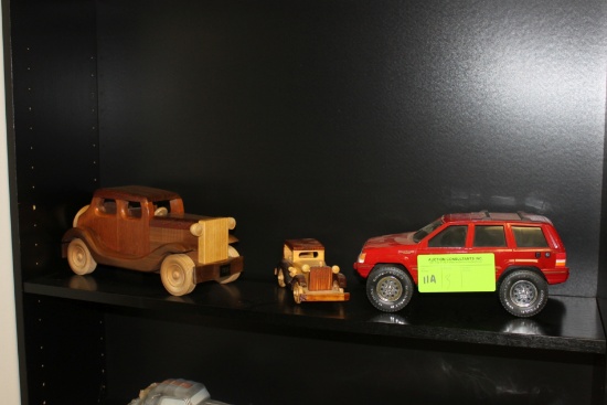 Two wooden automobiles, one with 1934 bumper sticker, and a Jeep Cherokee b