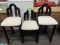 Three black lacquer and cream upholstered barstools