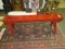 Red lacquered antique trestle bench with decorative apron carvings, dated l