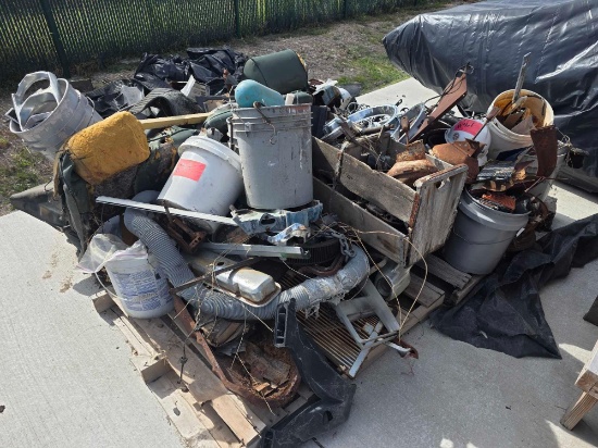 Mixed pile of unsorted scrap metal, automotive parts, wiring, discarded plastic buckets, torn seats