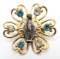 Unique Gold Tone Pin with Tiny Statue Center and Blue and Clear Stones