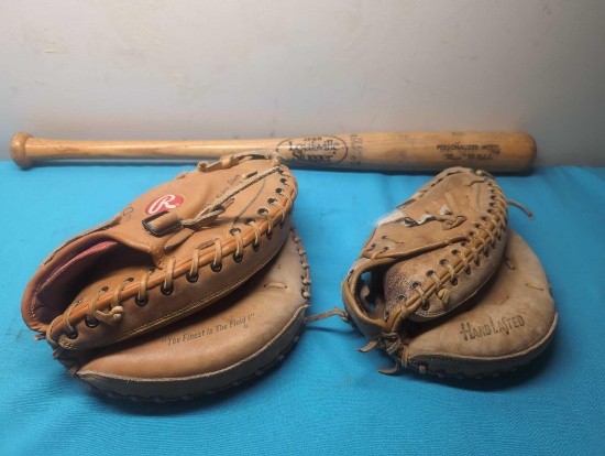 2 baseball catchers mitts and bat