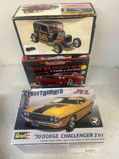 two Dodge Challenger and one Ford Victoria, car models in open boxes