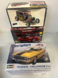 two Dodge Challenger and one Ford Victoria, car models in open boxes