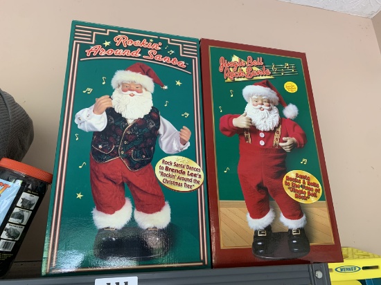Two Animatronic Santa Claus Christmas figures in boxes.