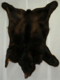 Black bear rug with hangers for wall mount ability, showing wear to one ear, measuring 68