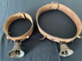 Two old brass bells on leather collars.