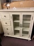 Cream colored cabinet with 4 drawers and glass doors