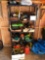 Metal shelf, battery charger, fuel cans, power cords, lights, gardening items, tarps