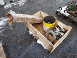 wooden box containing large clevis, pipe fittings, casters, and dump cylinder