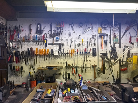 large grouping of hand, tools and hardware on workbench and pegboard