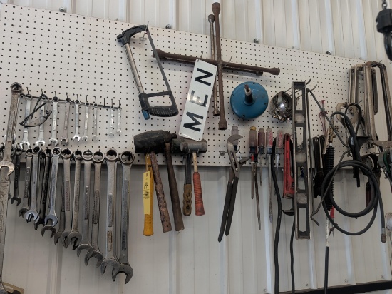 Contents of wall pegboard: Men sign, wrenches, rubber mallets, and more