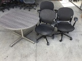 Three black office chairs with round lobby table