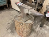 Anvil mounted on log.