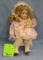 Vintage porcelain child doll clutching a doll