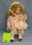 Vintage porcelain child doll clutching a doll