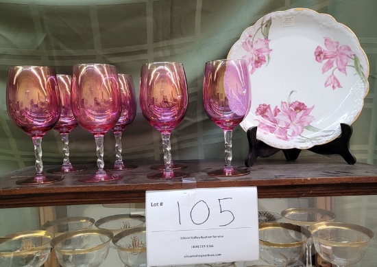 Seven cranberry wine glasses and floral plate