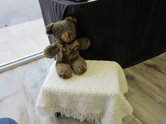 Vintage stuffed bear on a bench with a blanket