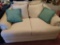 Beige fabric love seat with teal pillows