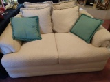 Beige fabric love seat with teal pillows
