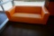 (1) Orange Faux Leather Couch.