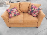 Burnt orange suede loveseat in used condition with no tears.