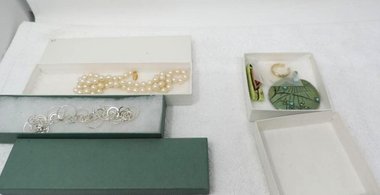 Silver colored bracelet and set of imitation pearl necklace.