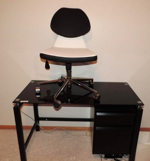 Black glass top desk with adjustable height office chair.
