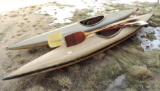Two vintage kayaks with 3 paddles.