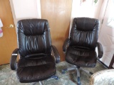 Two brown faux leather office chairs.